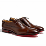 Čevlji Matej Oxford Royal Brogue znamke Mila Ljubljana, rjavi usnjeni moški gležnarji z brogue detajli na beli podlagi.