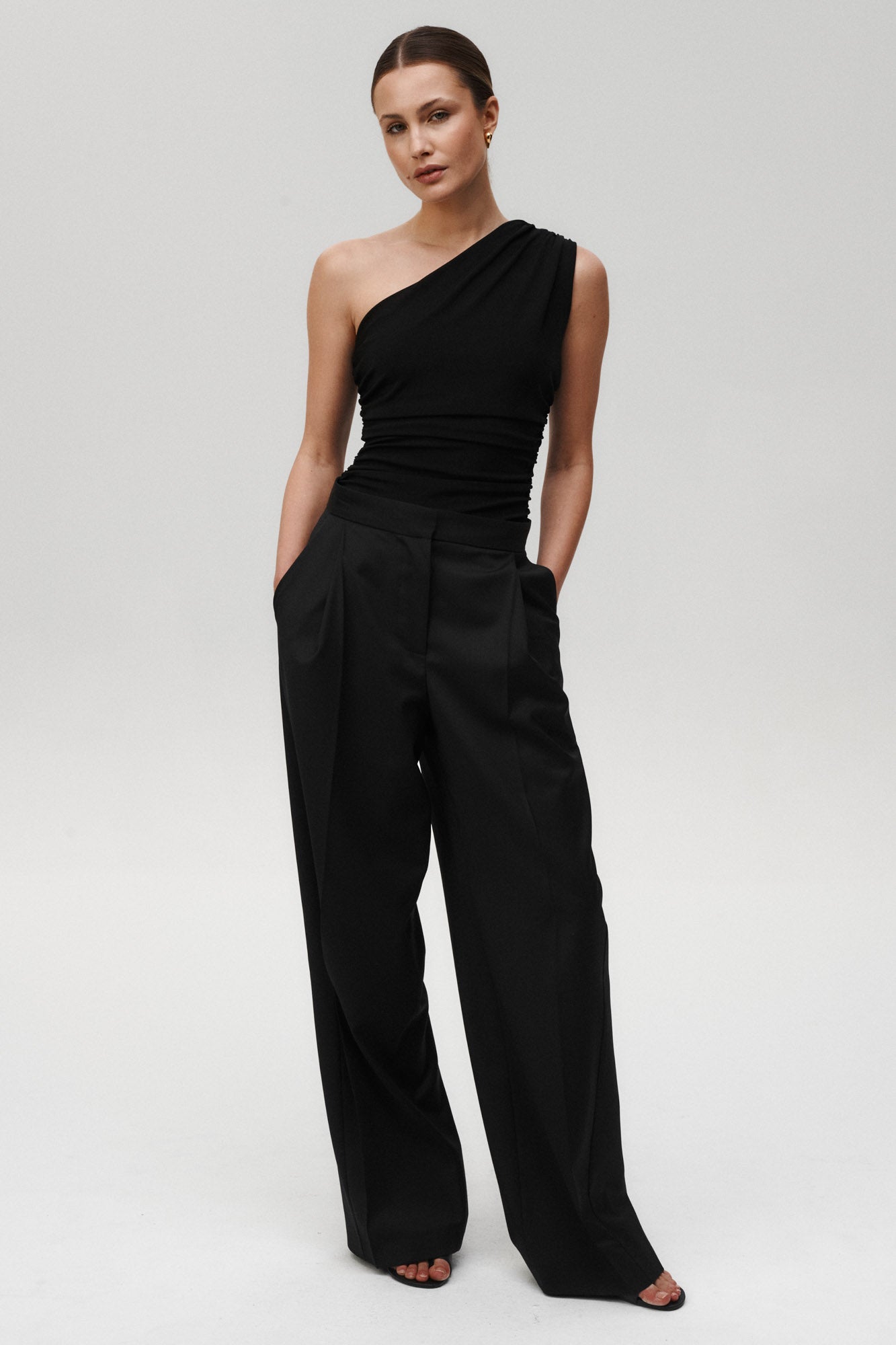 Črna Flair bodysuit Mila Ljubljana, elegant in oprijeten kroj, prikazan na modelu na beli podlagi.