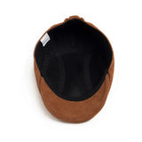 Alma Ljubljana klasična suede beret v rjavi barvi, prikazana na glavi modela, elegantno in modno dodatno za glavo.
